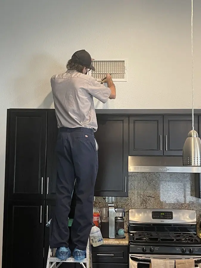 Technician inspecting an air vent during HVAC service in Newfane